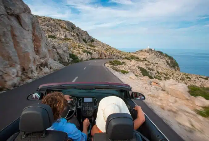 two men Driving a convertible through mountainous terrain.