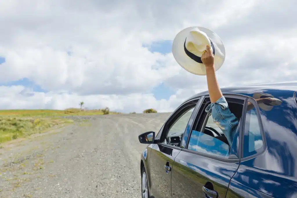 man holding a cap with his arms outside the car window