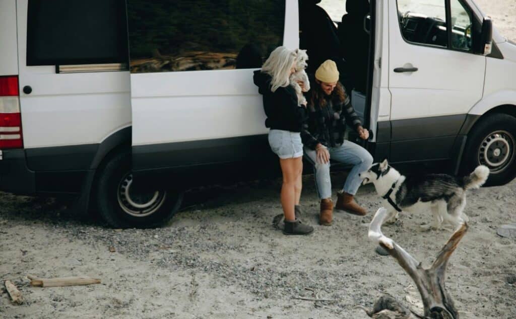 man and woman with a dog next to a camper van